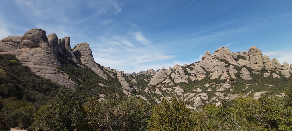 Wide-angle view from Montserrat highlighting the contrast between rocky cliffs and expansive forested areas below in Catalunya, Spain.