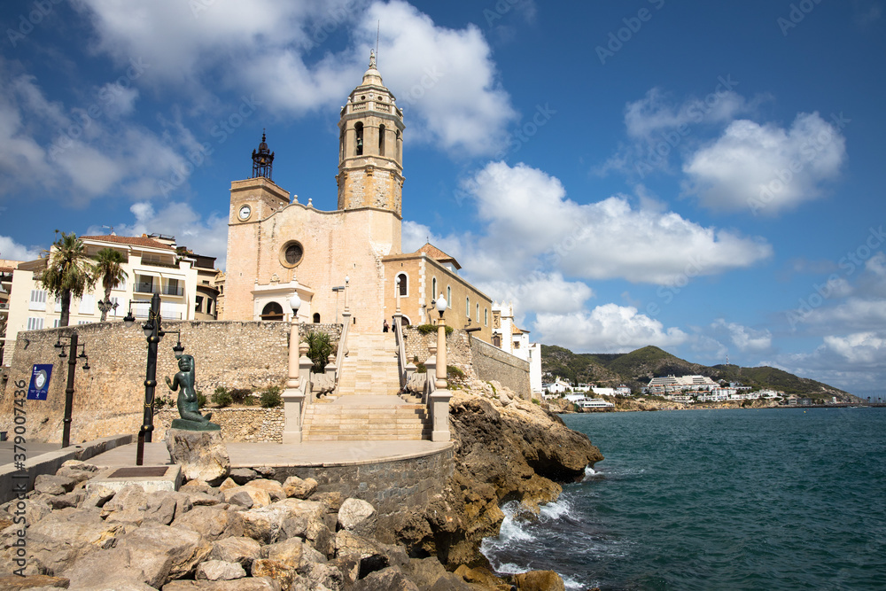 Church of Sant Bartomeu i Santa Tecla standing above Sitges’ beach on a sunny day, a hallmark of the Catalonian coast.