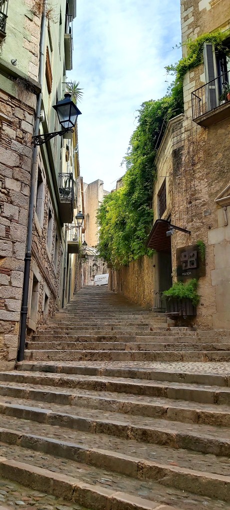 Cobblestone street in Girona’s old town, surrounded by stone buildings and narrow medieval pathways.