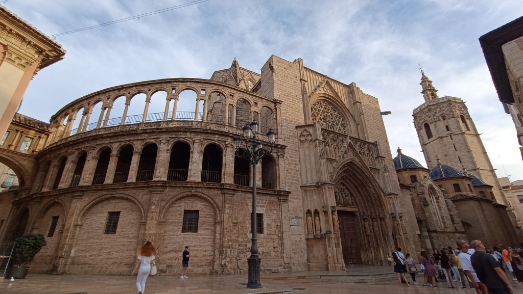 Valencia Cathedral viewed from the surrounding plaza with people walking nearby