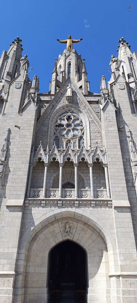 Exterior view of the Temple of the Sacred Heart of Jesus on Tibidabo, with its neo-Gothic façade and tall spires reaching into the sky.
