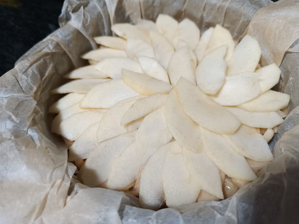 Decorated pear pie topped with thin pear and apple slices brushed with peach jam.
