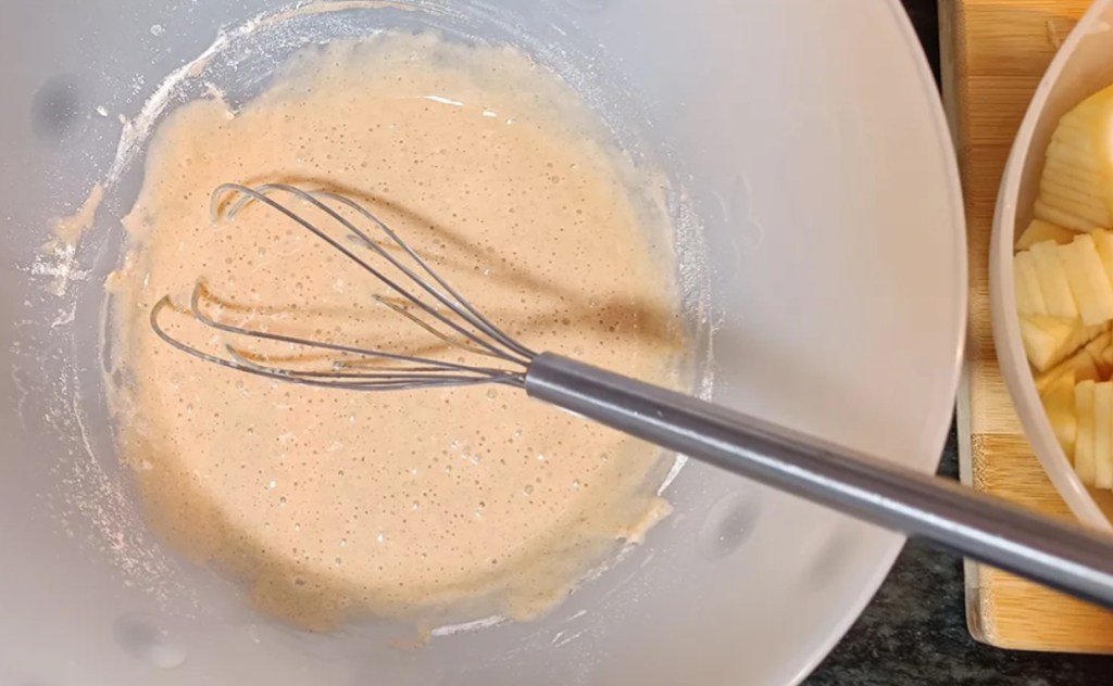 Preparing pear pie filling by whisking eggs, sugar, cinnamon, vanilla, and lemon juice in a mixing bowl.