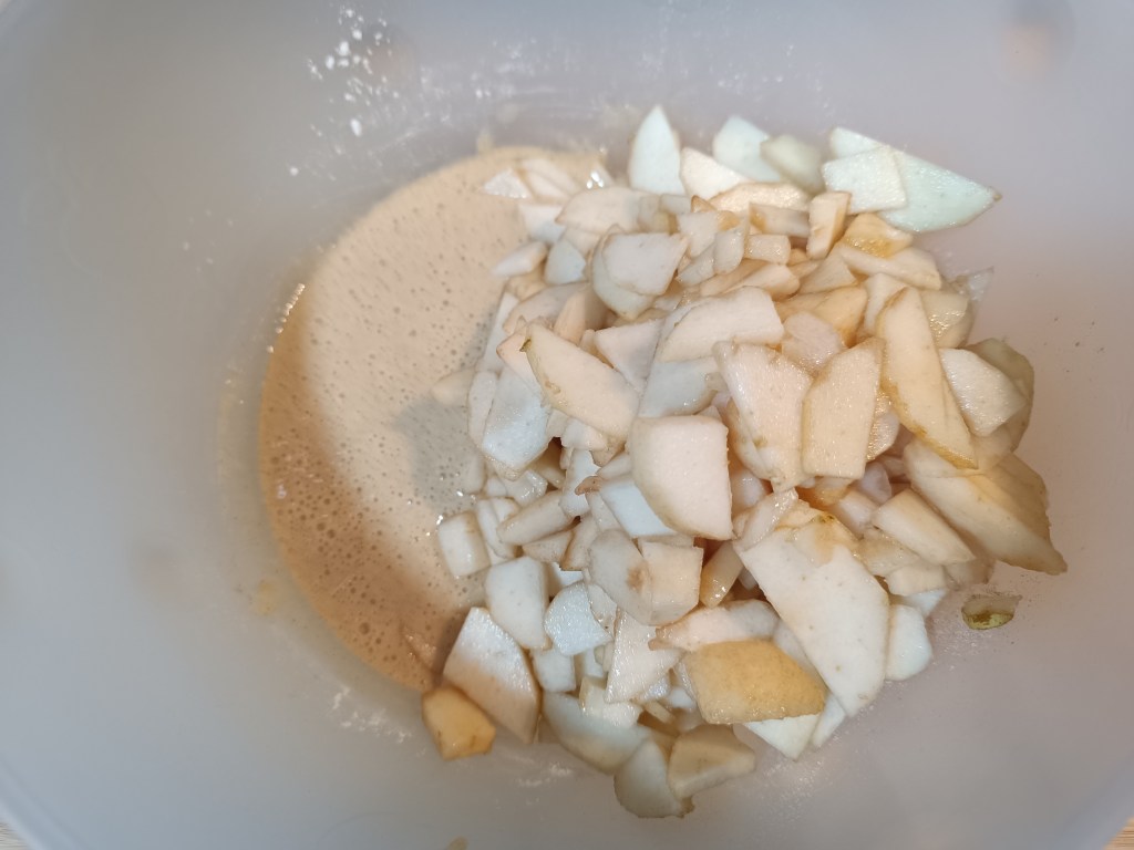 Close-up of thin pear slices being folded into the pear pie dough mixture