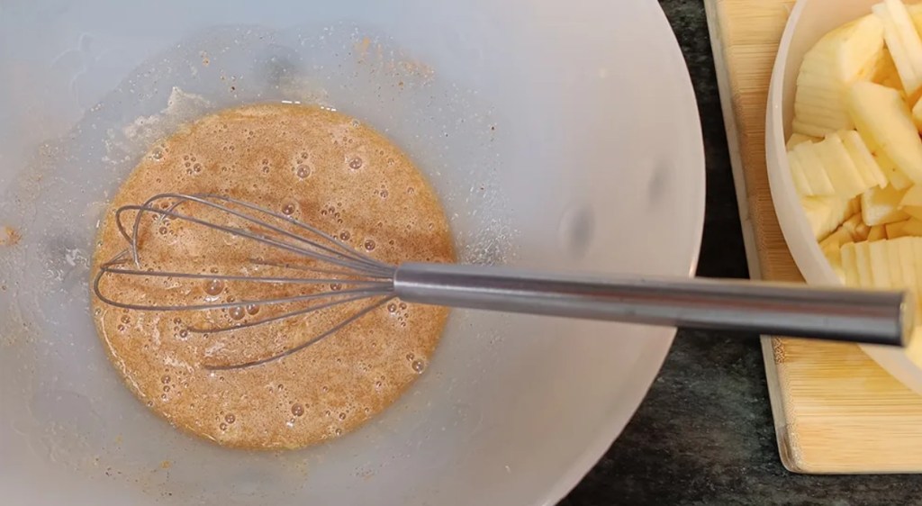 Mixing dry ingredients—flour, baking soda, and salt—into the wet pear pie mixture in a large bowl.