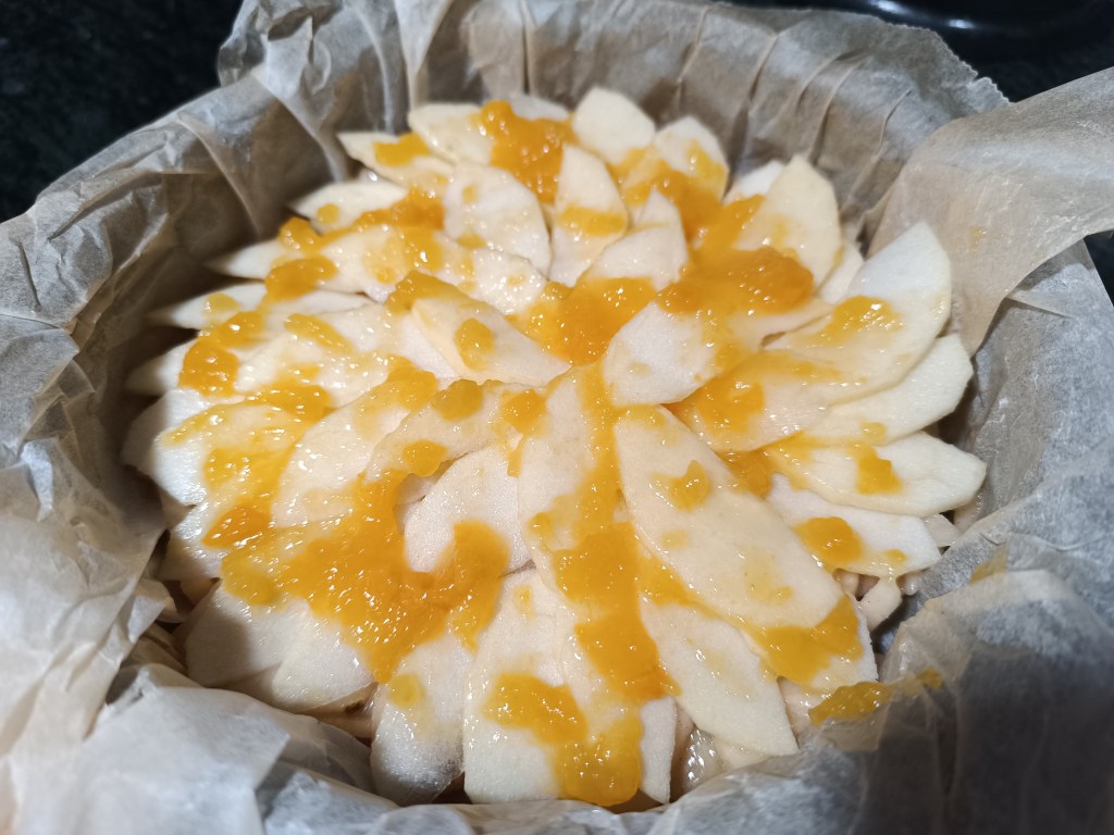 Homemade pear pie beautifully arranged with pear slices on top and coated in glossy peach jam.