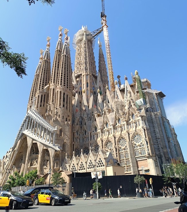 The ornate façade and towering spires of the Sagrada Familia cathedral in Barcelona, Spain, photographed from the outside under clear daylight.