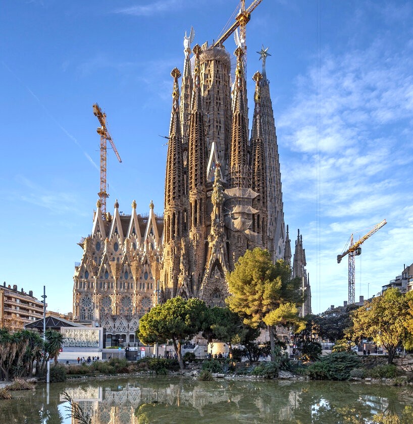 Exterior view of the Sagrada Familia cathedral in Barcelona, Spain, with detailed spires against a blue sky.