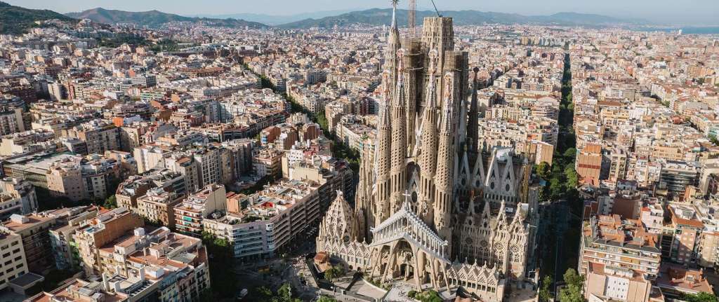 Exterior view of the Sagrada Familia cathedral in Barcelona, Spain, with detailed spires against a blue sky.