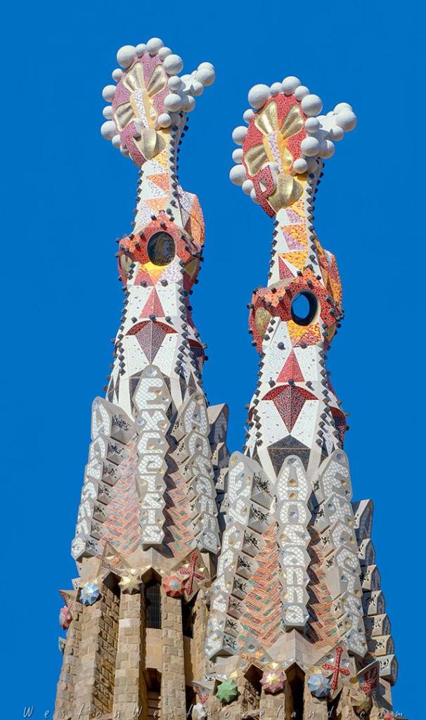 Close-up of a mosaic-covered tower spire at the Sagrada Familia, decorated in colorful ceramic trencadís tiles.