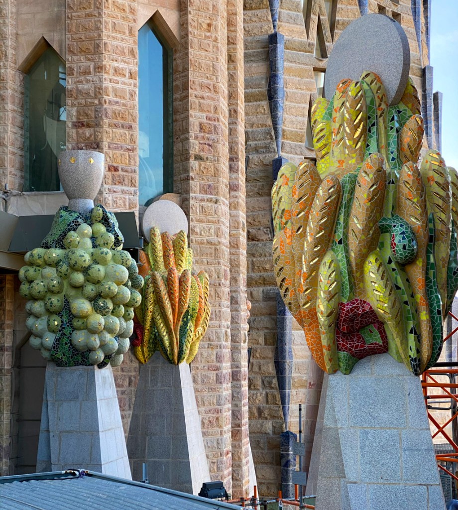 Detail of a pinnacle at the Sagrada Familia adorned with mosaics shaped like clusters of fruit, symbolizing abundance and creation.