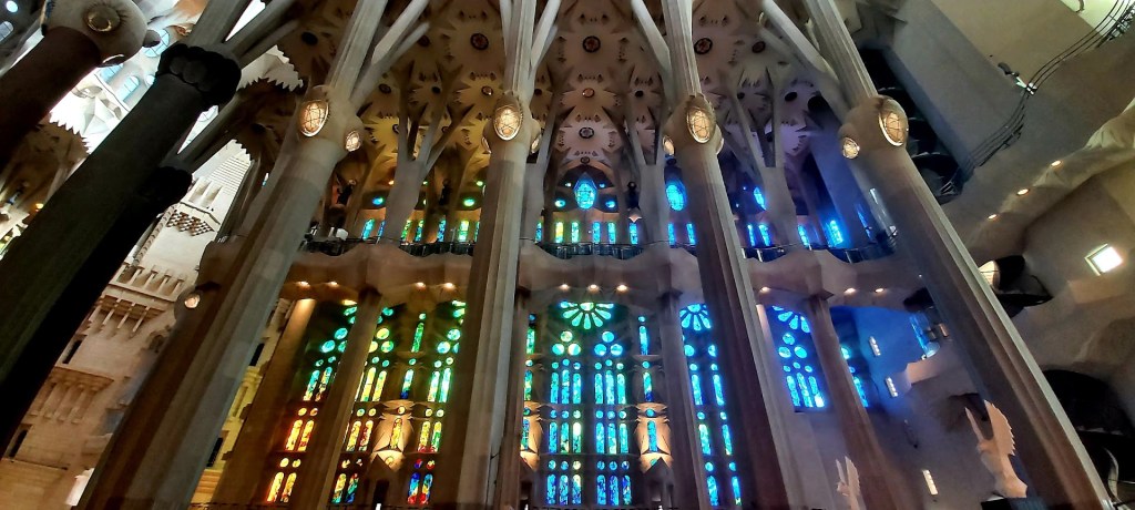 Detailed view of green-toned stained-glass windows inside the Sagrada Familia illuminating the stone carvings below