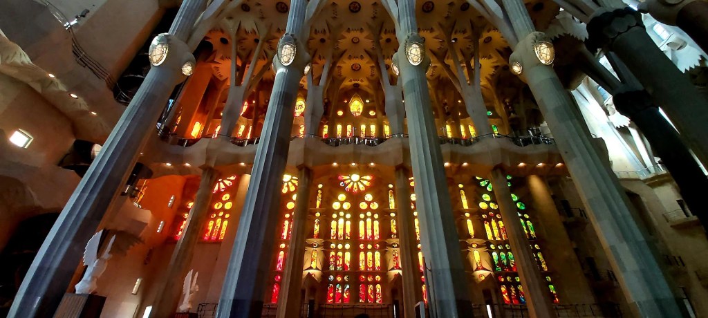 Close-up of stained-glass windows inside the Sagrada Familia casting warm red and orange light across the interior columns