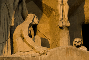 Close-up of the skull sculpture beneath the cross on the Passion façade of the Sagrada Familia, symbolizing Golgotha