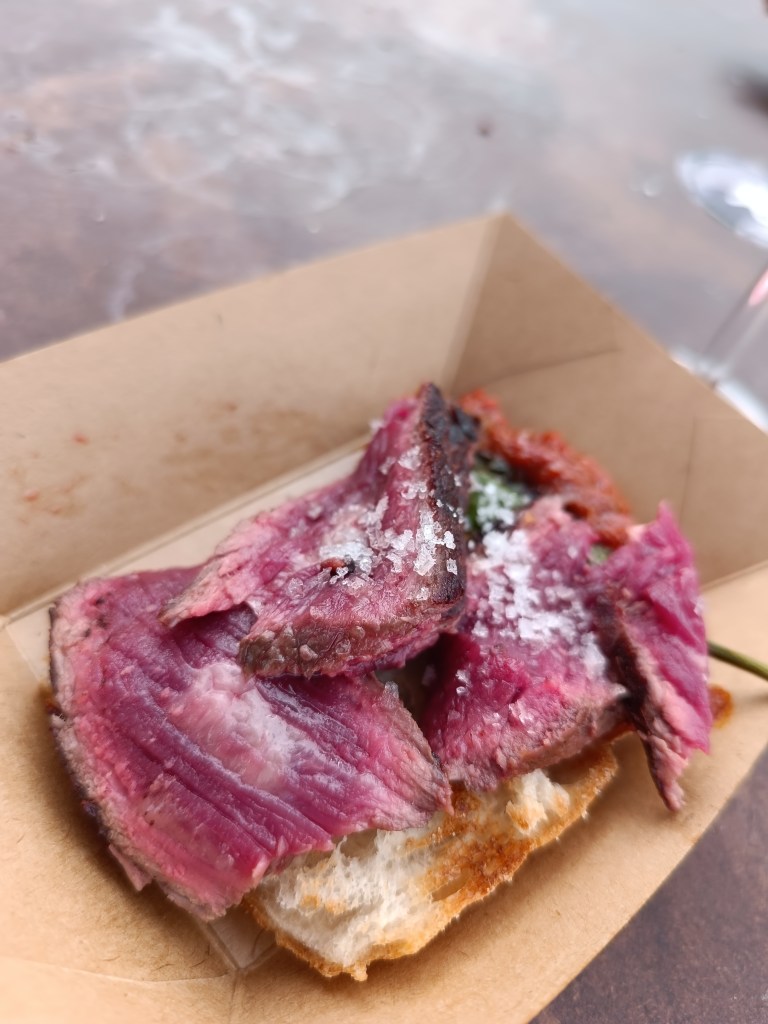 Fire-based cooking setup with chefs working around open flames at Meat & Fire.