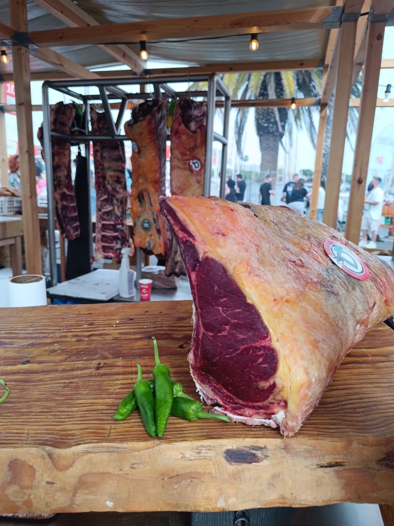 Close-up of meat sizzling on a grill with flames and smoke rising.