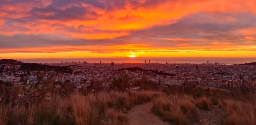Sunset view along Carretera de les Aigรผes with Barcelona spread out below and the sea on the horizon.
