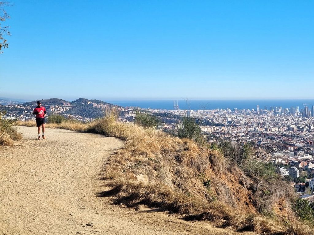 People walking along Carretera de les Aigรผes as the city lights turn on at dusk.
