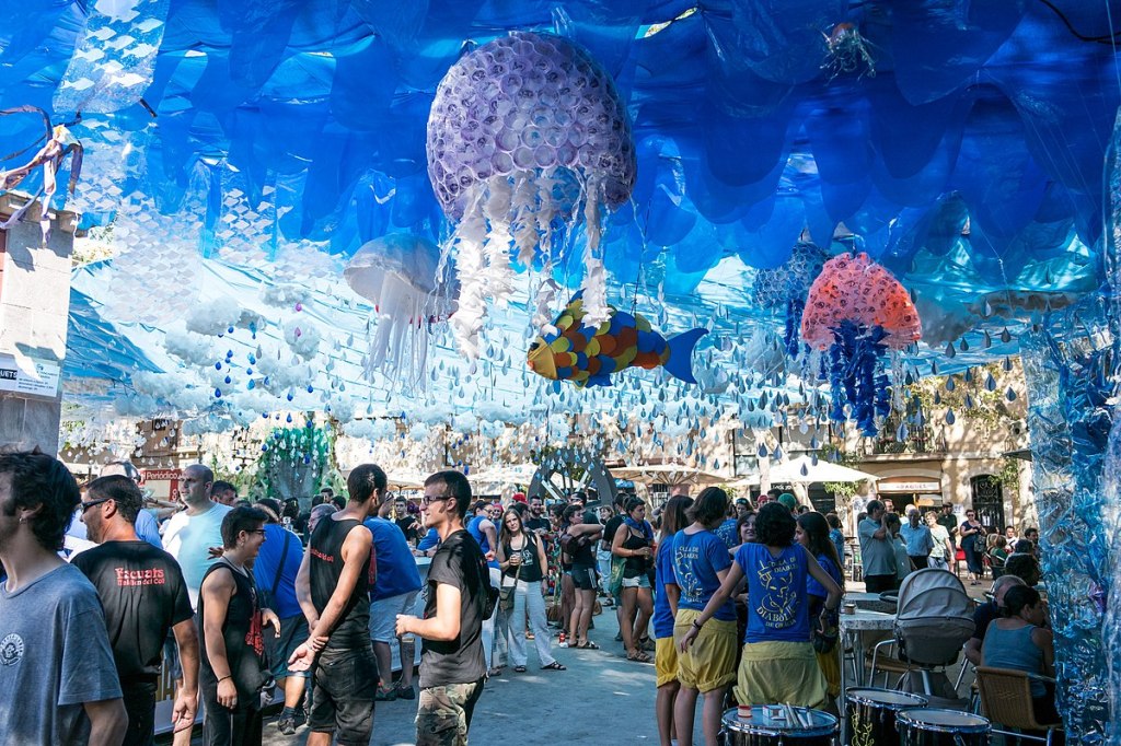 People walking beneath elaborate street decorations created by local residents.