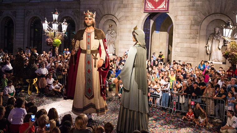 Giant papier-mâché figures dancing through the streets of Barcelona during a local festival.