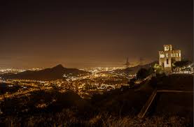 View from Mirador de Torre Barรณ overlooking Barcelona from the hilltop castle ruins at sunset.