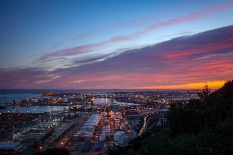 Sunset over Barcelona and the port from Montjuรฏc, with city rooftops and the sea in the distance.