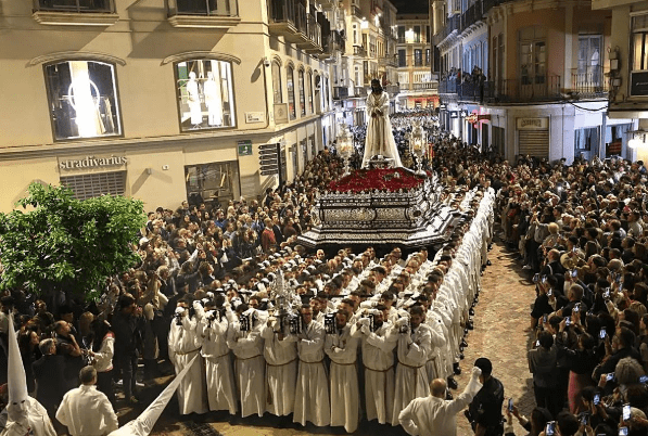 Religious procession during Semana Santa with a statue of the Virgin carried through the street.