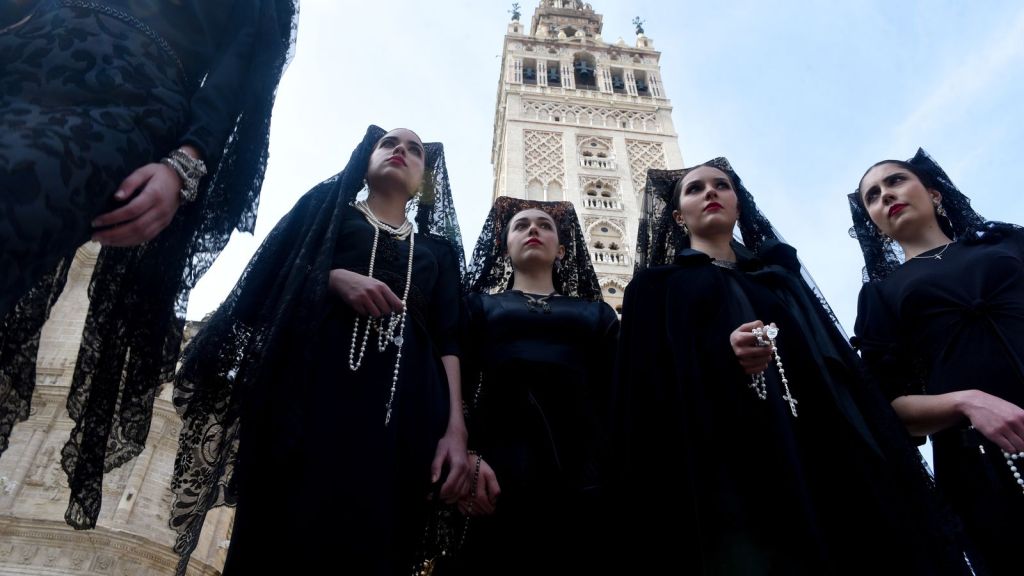 Semana Santa procession moving slowly through the city with candles and music.