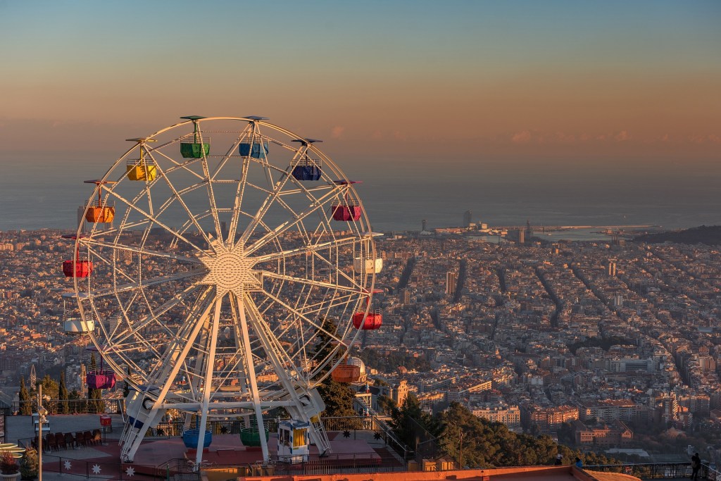 Golden hour from Tibidabo with Barcelona glowing below and pastel sunset colors above.