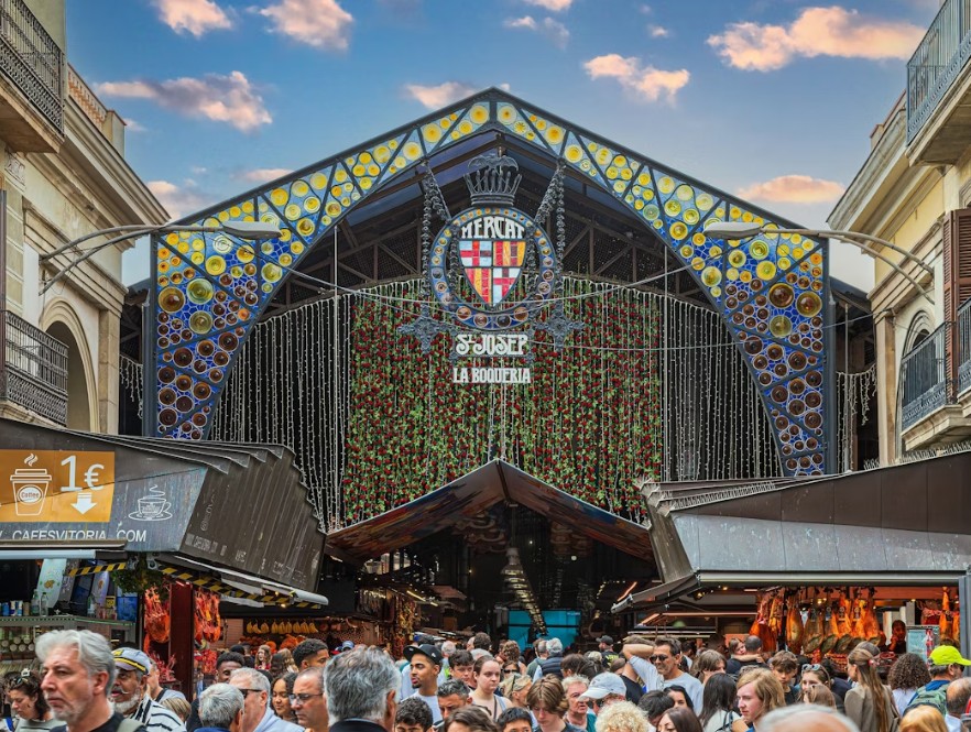 La Boqueria market in Barcelona, with colorful stalls of fresh fruit, seafood, and local foods bustling with shoppers